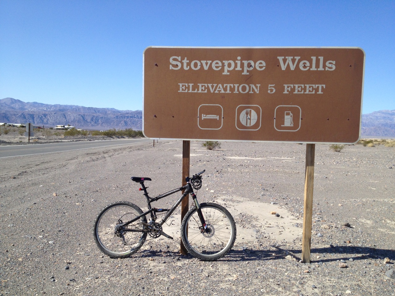 My trusty bicycle resting against the sign for Stovepipe Wells after the ride.