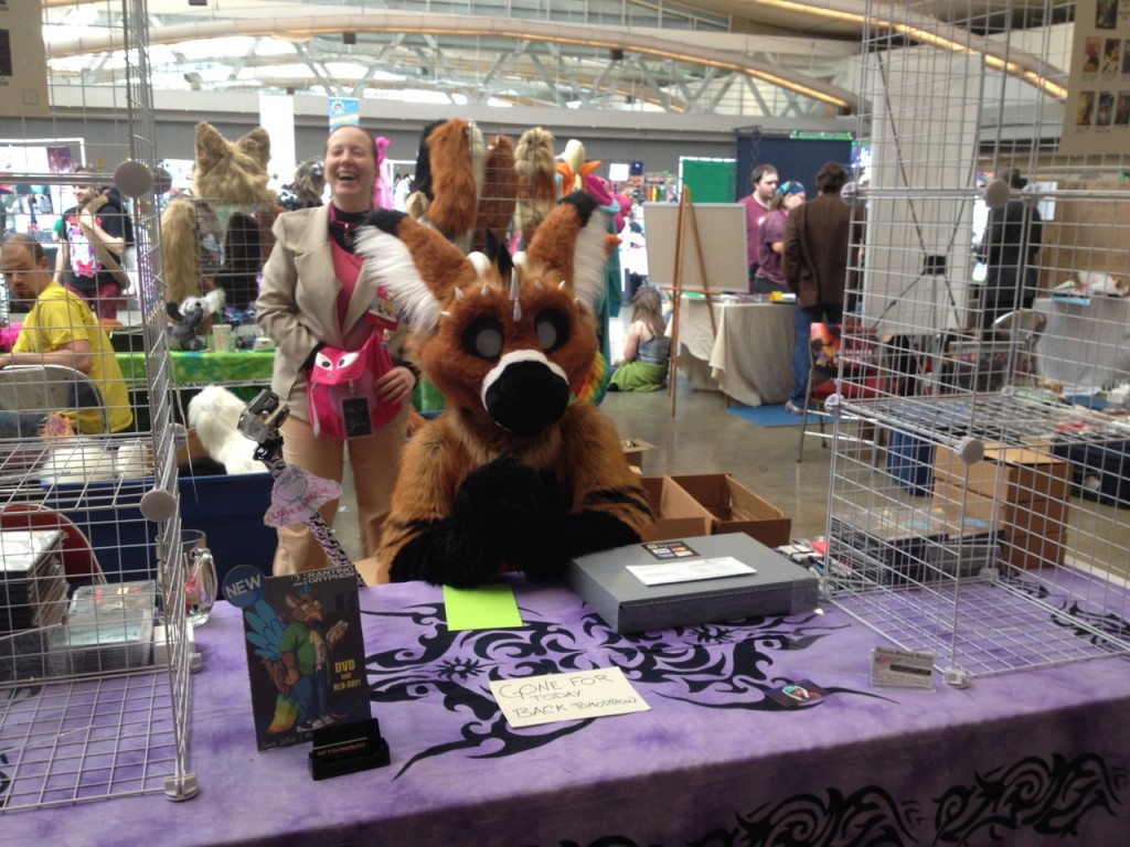 My friend Zylana (in back) and the fursuit performer Telephone, at 2's dealer table.